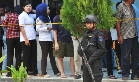 Beberapa anggota Polisi bersenjata lengkap tengah berjaga di depan Ruangan Instalasi Forensik RS Bhayangkara, Palu, Sulawesi Tengah, Selasa (19/7). 