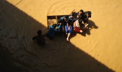 Beberapa bocah melintasi genangan banjir ddi Desa Tanjungsari, Kabupaten Tasikmalaya, Jawa Barat, Kamis (17/3).