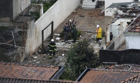 Beberapa orang sedang bekerja di lokasi jatuhnya pesawat kandidat presiden Brasil, Eduardo Campos di Santos, Rabu (13/8)