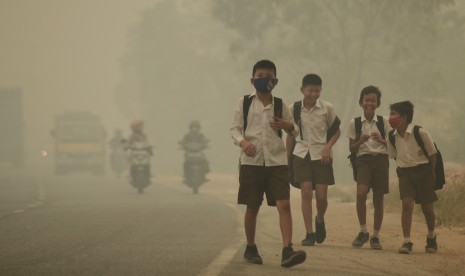 Beberapa pelajar SMP 15 Kota Jambi berjalan pulang menembus kabut asap dari sekolah di Jalan Lingkar Timur, Jambi, Selasa (29/9). 