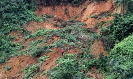 Beberapa petugas BPBD Kabupaten Solok Selatan berjalan di atas material longsor yang menimbun badan jalan di Jorong Pisulang Lolo, Kecamatan Pantai Cermin, Kabupaten Solok Selatan, Sumatera Barat, Rabu (10/2). 