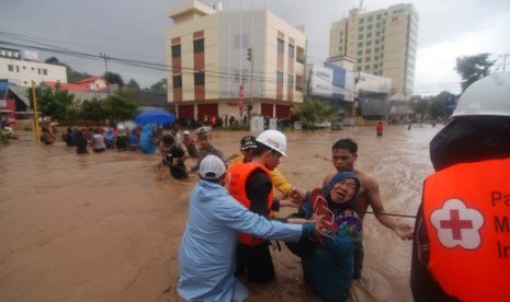  Beberapa petugas Palang Merah Indonesia (PMI) Sulut membantu warga menyeberangai banjir di Kelurahan Wenang, Manado, Sulawesi Utara, Rabu (15/1).   (Antara/Fiqman Sunandar)