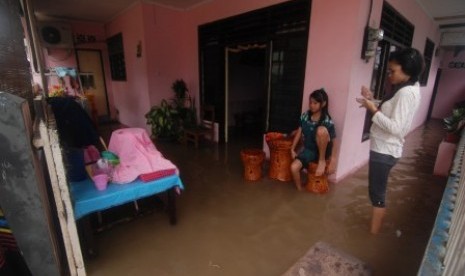 Beberapa warga berada dirumahnya yang dilanda banjir di kelurahan Mahakam Lingkungan IV, kecamatan Singkil, kota Manado, Sulawesi Utara, Minggu (17/2). Akibat diguyur hujan selama dua hari disejumlah lokasi rawan banjir di kota Manado digenangi air mencapa