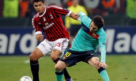 Bek AC Milan Thiago Silva berduel dengan penyerang Barcelona Lionel Messi