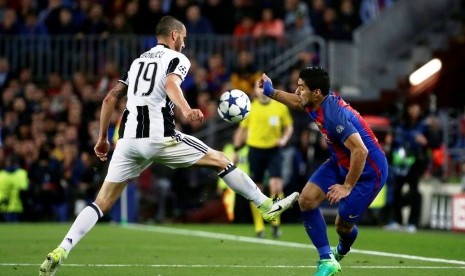 Bek Juventus Leonardo Bonucci (kiri) saat menahan upaya serangan penyerang Barcelona Luis Suarez.