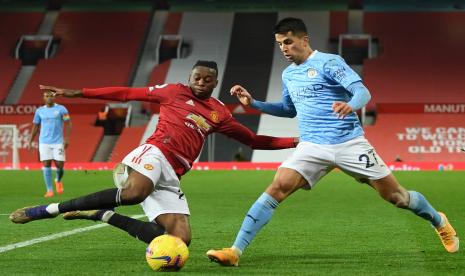 Bek kanan Manchester United (MU) Aaron Wan-Bissaka (kiri) berusaha mengadang pemain Manchester City Joao Cancelo pada lanjutan Liga Primer Inggri 2020/2021 di Stadion Old Trafford, Ahad (13/12) dini hari WIB.