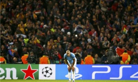 Bek Manchester City, Vincent Kompany, tertunduk lesu setelah Barcelona mencetak gol keduanya lewat Dani Alves dalam leg pertama babak 16 besar Liga Champions di Stadion Etihad, Manchester, Selasa (18/2). 