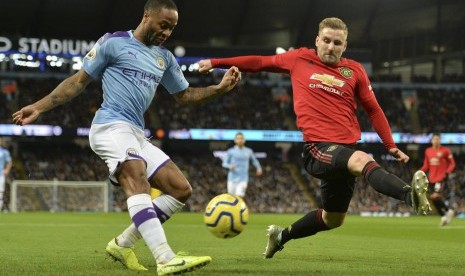 Bek Manchester United (MU) Luke Shaw (kanan) berusaha menahan tendangan winger Manchester City Rahem Sterling. 