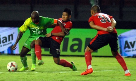 Bek Pelita Bandung Raya Wildansyah (tengah) berusaha mengadang laju pemain Persebaya Emanuel Kenmogne, Ahad (26/10).