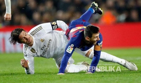 Bek Real Madrid Sergio Ramos mengganjal Lionel Messi  pada laga El Clasico antara FC Barcelona melawan Real Madrid di Camp Nou, Barcelona, Spanyol, Kamis (19/12) dini hari.