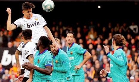 Bek Valencia, Gabriel Paulista (tengah) menyundul bola di antara kawalan pemain Barcelona pada laga La Liga di Stadion Mestalla, Sabtu (25/1). Valencia menang 2-0.