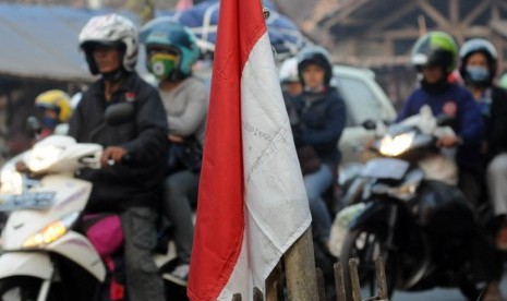   Bendera merah putih terlihat sebagai latar depan pemudik bersepeda motor yang melintasi jalur alternatif Cilamaya-Cikalong, Karawang, Jawa Barat, Jumat (17/8).(Aditya Pradana Putra/Republika)