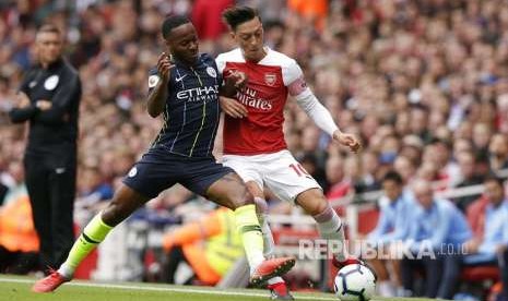 Raheem Sterling (kiri) Mesut Ozil (kanan) berebut bola pada laga Liga Primer Inggris antara Arsenal dan Manchester City di Emirates Stadium, London, Ahad (12/8)