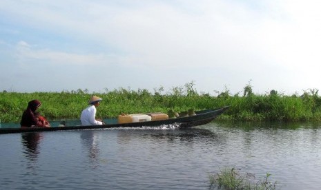 Bersama suami dan anak, perempuan di Daha Selatan sering bolak-balik ke kebun naik perahu kelotok sekitar satu jam perjalanan.