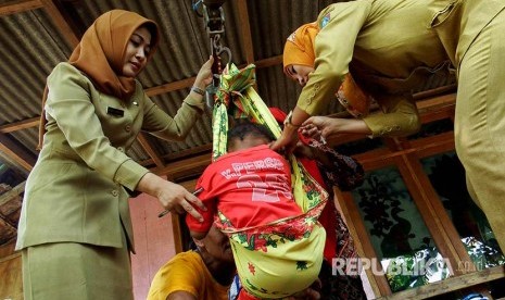 Bidan desa Nurul Indawati (kiri) dibantu bidan mandiri Rurita (kanan) menimbang balita di Dusun Nampu, Jombang.