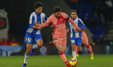 Bintang Barcelona Lionel Messi (tengah) melewati adangan pemain Espanyol.