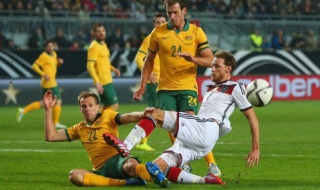  Bintang Jerman Benedikt Hoewedes ditackle oleh Alex Wilkinson (22) dari Australia.