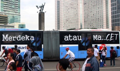 Bis TransJakarta yang bertuliskan Merdeka Atau Macet melintasi area Car Free Day di kawasan Bundaran HI, Jakarta, Minggu (14/8). 