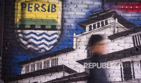 Bobotoh alias pendukung Persib berjalan di depan mural Persib di Bandung, Jawa Barat, Selasa (2/10). 