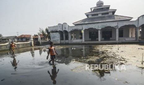 Bocah bermain di halaman Masjid yang tergenang banjir rob di Desa Pantai Bahagia, Muaragembong, Kabupaten Bekasi, Jawa Barat, Selasa (6/8/2019). 