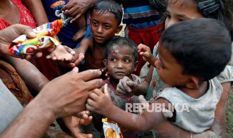 Bocah pengungsi Rohingya berbagi makanan setelah melintasi pesawahan setelah melintasi perbatasan Bangladesh-Myanmar di Teknaf, Bangladesh, Rabu (6/9).