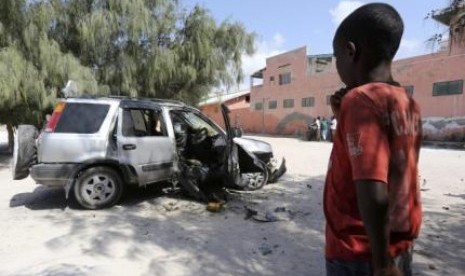 Bocah Somalia memerhatikan rongsokan mobil yang hancur akibat ledakan bom di Ibu Kota Mogadishu.