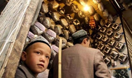 Bocah Uighur di Xinjiang ikut ayahnya berjualan kopiah. 