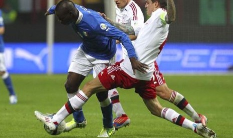 Bomber Italia, Mario Balotelli, hendak diganjal bek Denmark, Daniel Agger, pada partai Rabu (17/10) dini hari tadi.