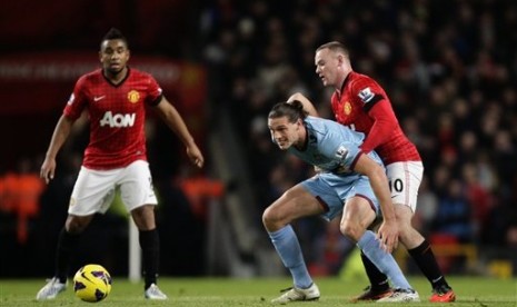 Bomber Manchester United (MU), Wayne Rooney, menjaga penyerang West Ham, Andy Carroll, sambil disaksikan gelandang MU, Anderson, pada laga di Old Trafford, Kamis (29/11) dini hari. MU menang 1-0 dan kokoh di puncak klasemen Liga Primer Inggris. 