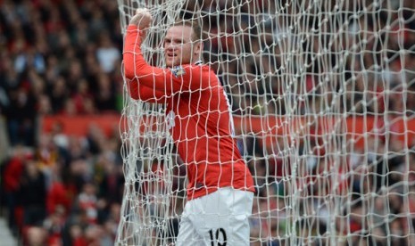 Bomber Manchester United Wayne Rooney memegang jaring gol saat laga melawan Swansea di Stadion Old Trafford, Manchester, Inggris, Minggu (6/5). Meski menang 2-0, MU masih tertinggal 8 gol dari rival sekota Manchester City.