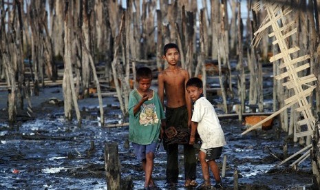 Boys walk through mud carrying items salvaged from the ruins of the burned neighbourhood in East Pikesake ward in Kyaukphyu November 5, 2012. Picture taken November 5.  