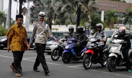   Bripka Novi dengan mengenakan seragam polisi berjilbab membantu warga menyeberang jalan di Bundaran HI, Jakarta Pusat, Senin (25/11).  (Republika/Yasin Habibi)