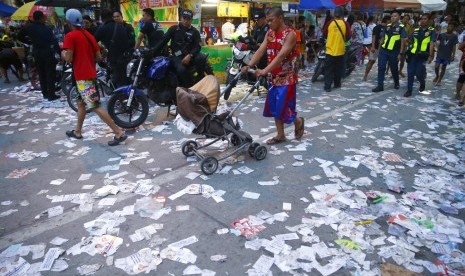 Brosur kampanye berserakan di luar sebuah tempat pemungutan suara pemilu paruh waktu di Manila, Filipina, Senin (13/5).