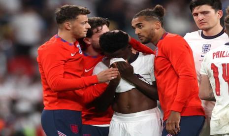 Bukayo Saka dari Inggris terlihat sedih setelah kalah dalam adu penalti saat rekan setimnya menghiburnya