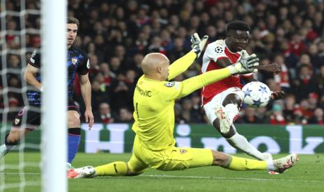 Bukayo Saka (kanan) dari Arsenal mencetak gol kedua timnya ke gawang Marko Dmitrovic (tengah) dari Sevilla pada pertandingan Grup B Liga Champions UEFA di Stadion Emirates, London, Kamis (9/11/2023). 