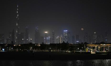 Bulan purnama terbit di atas cakrawala kota dengan menara tertinggi di dunia, Burj Khalifa, di Dubai, Uni Emirat Arab, Selasa, 14 Juni 2022.