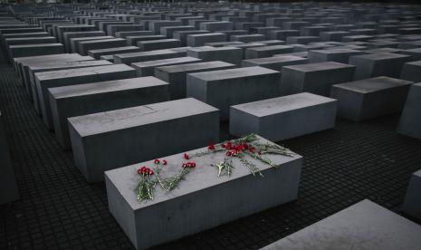 Bunga-bunga tergeletak di atas lempengan beton Memorial Holocaust. Rumania yang merupakan sekutu Nazi memutuskan untuk menjadikan Holocaust dan sejarah Yahudi sebagai bagian dari kurikulum sekolah. 