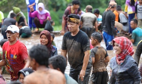 Bupati Bandung H Dadang M Naser (berikat kepala) tengah bermain di kubangan dengan warga Kampung Cilodong, Desa Karangtunggal, Kecamatan Paseh, Kabupaten Bandung, Sabtu (15/4).