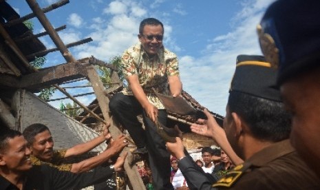 Bupati Banyuwangi Abdullah Azwar Anas (tengah) menurunkan genteng rumah penduduk ketika berlangsungnya Festival Bedah Rumah di Kelurahan Sobo, Banyuwangi, Jawa Timur, Rabu (18/2). Festival yang membedah 241 rumah warga miskin itu dananya dihimpun dari dona