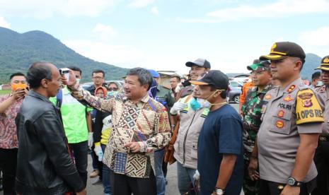 Bupati Garut Rudy Gunawan memeriksa suhu tubuh dan membagikan hand sanitizer ke para pengemudi dan penumpang kendaraan yang masuk ke Garut, Ahad (22/3).