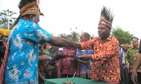 Bupati Jayapura Mathius Awoitouw (kanan) menyerahkan peraturan bupati tentang pengakuan dan perlindungan masyarakat adat di Kabupaten Jayapura kepada wakil masyarakat adat.