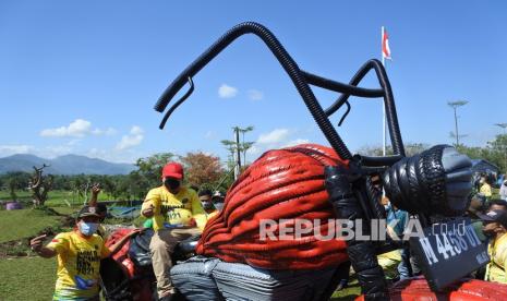 Bupati Jember Hendy Siswanto (kedua kiri) menaiki replika motor besar yang terbuat dari bahan bekas di tempat pembuangan akhir (TPA) sampah Pakusari, Jember, Jawa Timur, Sabtu (18/9/2021). Pemerintah Kabupaten Jember bersama aktivis lingkungan berkampanye memilih dan memilah sampah sebelum dibuang ke TPA sampah bertepatan dengan peringatan Hari World Cleanup Day 2021 pada 18 September, dengan mengolahnya menjadi replika motor besar, dinosaurus, dan rumah botol. 