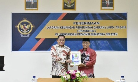 Bupati Musi Banyuasin (Muba) Dodi Reza Alex (kiri) menyerahkan Laporan Keuangan Pemerintah Daerah (LKPD) Tahun Anggaran 2018 yang diterima Kepala Perwakilan Badan Pemeriksa Keuangan (BPK) RI Sumsel Maman Abdul Rahman (kanan) di kantor BPK RI Perwakilan Sumsel, Kamis (17/1). 