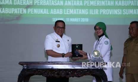 Bupati Musi Banyuasin (Muba) pada Dodi Reza Alex Deputi Direksi Wilayah Sumatera Selatan, Kepulauan Bangka Belitung, dan Bengkulu BPJS Kesehatan Erna Wijaya Kesuma serahkan cendera mata pada Launching Universal Health Coverage (UHC) dan Penandatanganan Nota Kesepahaman (MoU) tentang kerjasama daerah perbatasan antara Pemkab Muba dengan Pemkab Penukal Abab Lematang Ilir (Pali), Senin (11/3) di Sekayu.