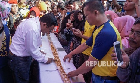 Bupati Pekalongan Asp Kholbihi (kiri) memotong getuk lindri pada perayaan syawalan di Kedungwuni, Kabupaten Pekalongan, Jawa Tengah, Sabtu (23/6).