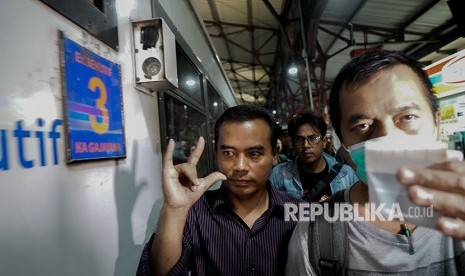 Bupati Purbalingga Tasdi (tengah), membuat tanda jari 'metal' saat akan dibawa ke Jakarta oleh petugas KPK, di Stasiun Purwokerto, Banyumas, Jawa Tengah, Senin (4/6). 