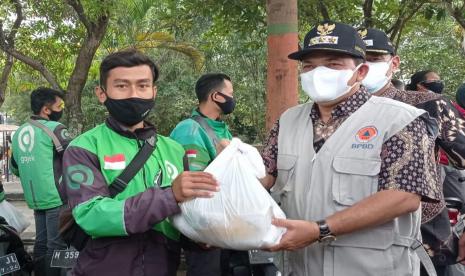 Bupati Semarang, H Ngesti Nugraha menyerahkan paket beras dan bahan kebutuhan pokok lain kepada driver ojol, di Jalan Ahmad Yani, Ungaran, Kabupaten Semarang, Sabtu (31/7). Selain driver ojol para pedagang PKL juga mendapatkan bantuan yang sama dari Pemkab Semarang.