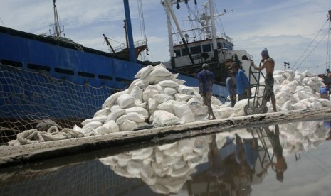 Buruh angkut memanggul tepung ke sebuah truk saat bongkar muat tepung sagu di Pelabuhan Cirebon, Jawa Barat, Selasa (3/4).