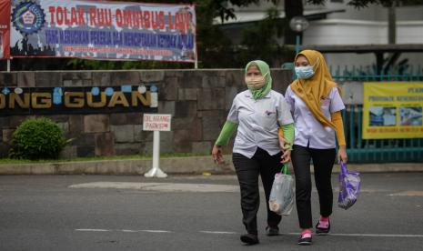 Buruh pabrik berjalan meninggalkan area pabrik pada saat jam pulang kerja di salah satu Pabrik di kawasan Ciracas, Jakarta Timur.