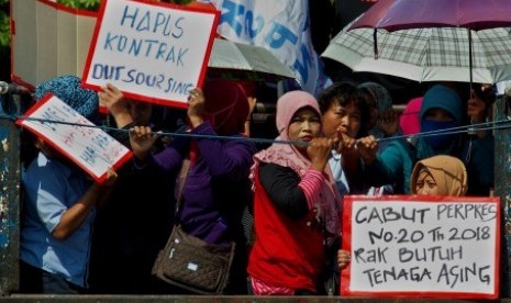 Buruh yang tergabung dalam Konfederasi Serikat Pekerja Nasional (KSPN) berada di atas bak truk sambil membawa poster, saat berunjuk rasa memperingati Hari Buruh Internasional, di Semarang, Jawa Tengah, Selasa (1/5). 